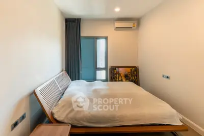 Modern bedroom with sleek design and natural light, featuring a stylish bed and air conditioning.