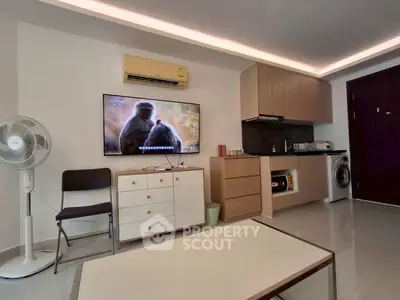 Modern living room with TV, kitchenette, and washing machine in stylish apartment.