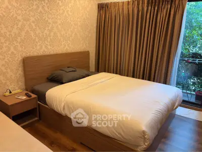 Cozy bedroom with elegant wallpaper and balcony view, featuring a comfortable bed and warm lighting.