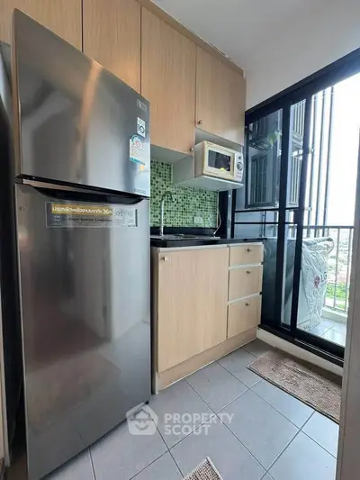 Modern kitchen with stainless steel fridge and microwave, featuring a balcony view.