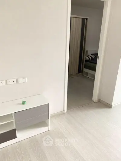 Modern minimalist interior with sleek flooring and open doorway leading to a cozy bedroom.
