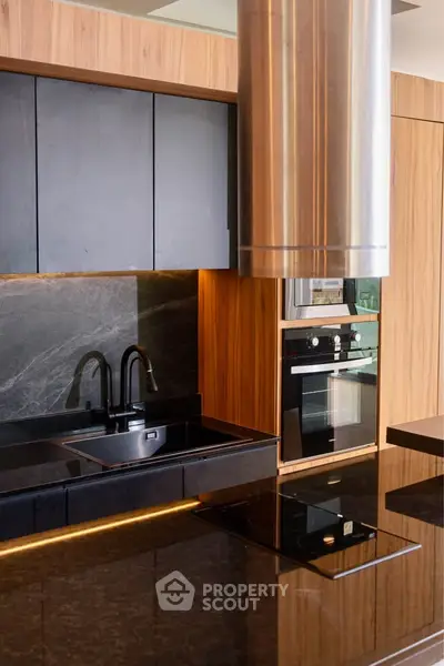 Modern kitchen with sleek black countertops and built-in oven, featuring elegant wood cabinetry.