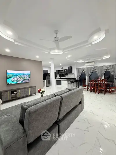 Spacious modern living room with open kitchen and elegant dining area, featuring sleek design and luxurious finishes.