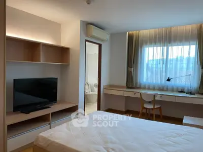 Modern bedroom with TV, desk, and window view in stylish apartment