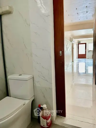 Spacious hallway with marble flooring and adjacent bathroom in modern apartment.