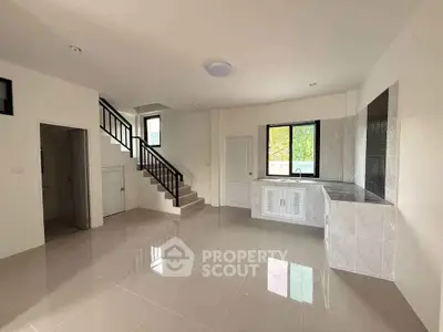 Spacious modern living room with sleek staircase and large window, perfect for natural light.