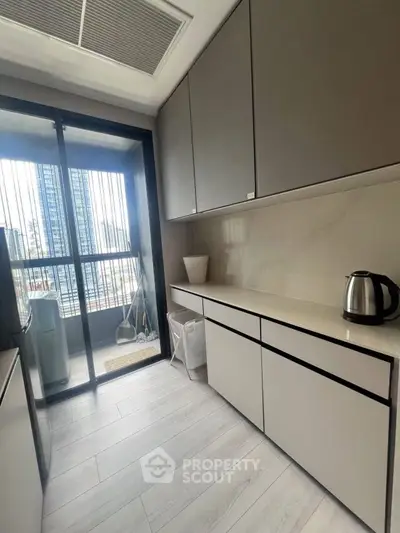 Modern kitchen with sleek cabinets and balcony view in urban apartment