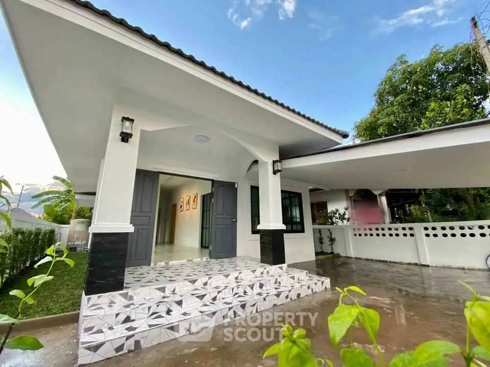Charming single-story home with covered carport and inviting front porch, surrounded by lush greenery.