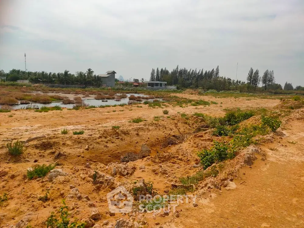 Expansive land plot with potential for development, surrounded by lush greenery and open skies.