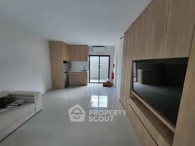 Modern open-plan living room with sleek kitchen and built-in TV unit
