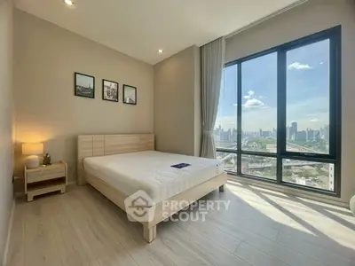 Spacious bedroom with large windows offering stunning city skyline views, modern decor, and natural light.