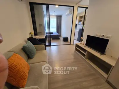 Modern apartment living room with cozy sofa and TV, open layout to bedroom