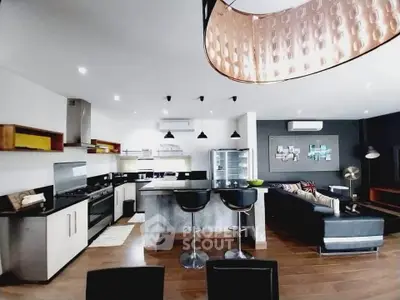 Modern open-layout kitchen and living room with stylish lighting and sleek appliances.