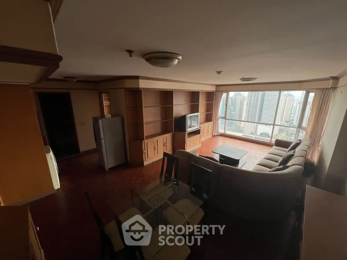 Spacious living room with city view, featuring modern furniture and large windows for natural light.