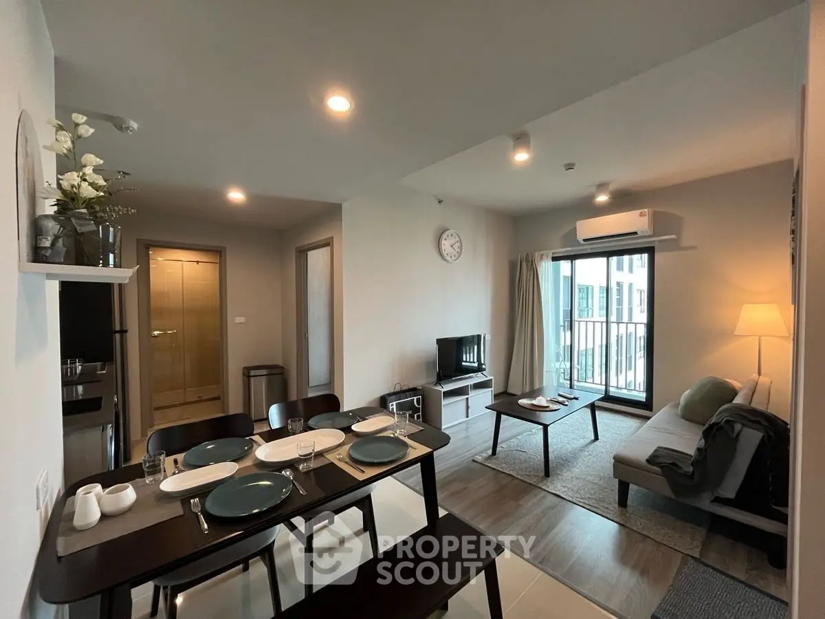 Modern open-plan living and dining area with balcony access in stylish apartment.