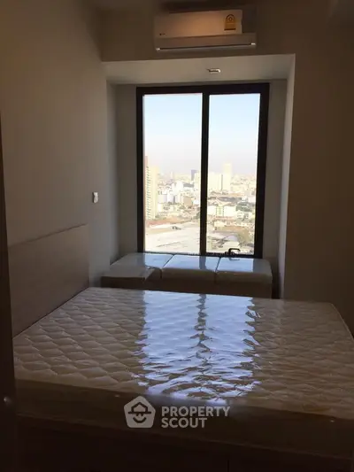 Cozy bedroom with large window offering stunning city view, perfect for urban living.