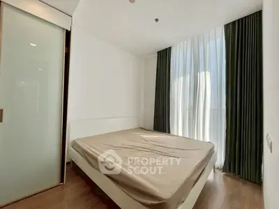 Spacious bedroom with large window and modern design in a luxury apartment.