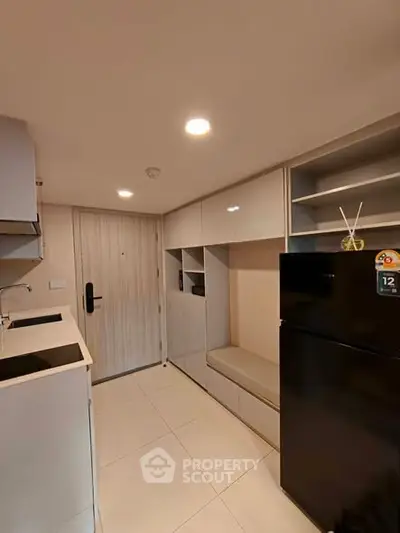 Modern compact kitchen with sleek cabinetry and black refrigerator