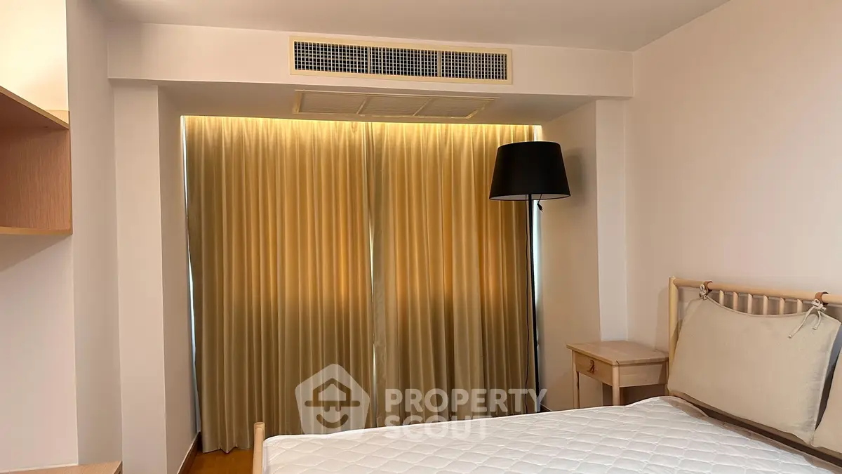 Cozy bedroom with elegant lighting and modern decor, featuring a comfortable bed and stylish floor lamp.