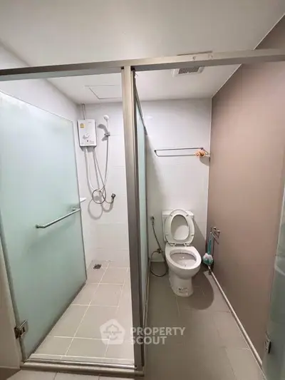 Modern bathroom with glass shower enclosure and toilet in sleek design.