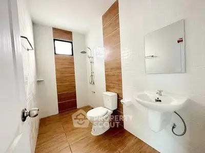 Modern bathroom with sleek fixtures and wood-style tiles, featuring a shower and toilet.
