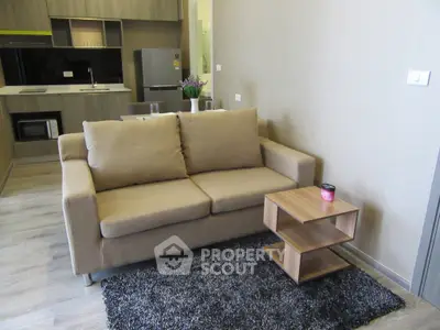 Modern living room with cozy sofa and stylish kitchen in open layout apartment.