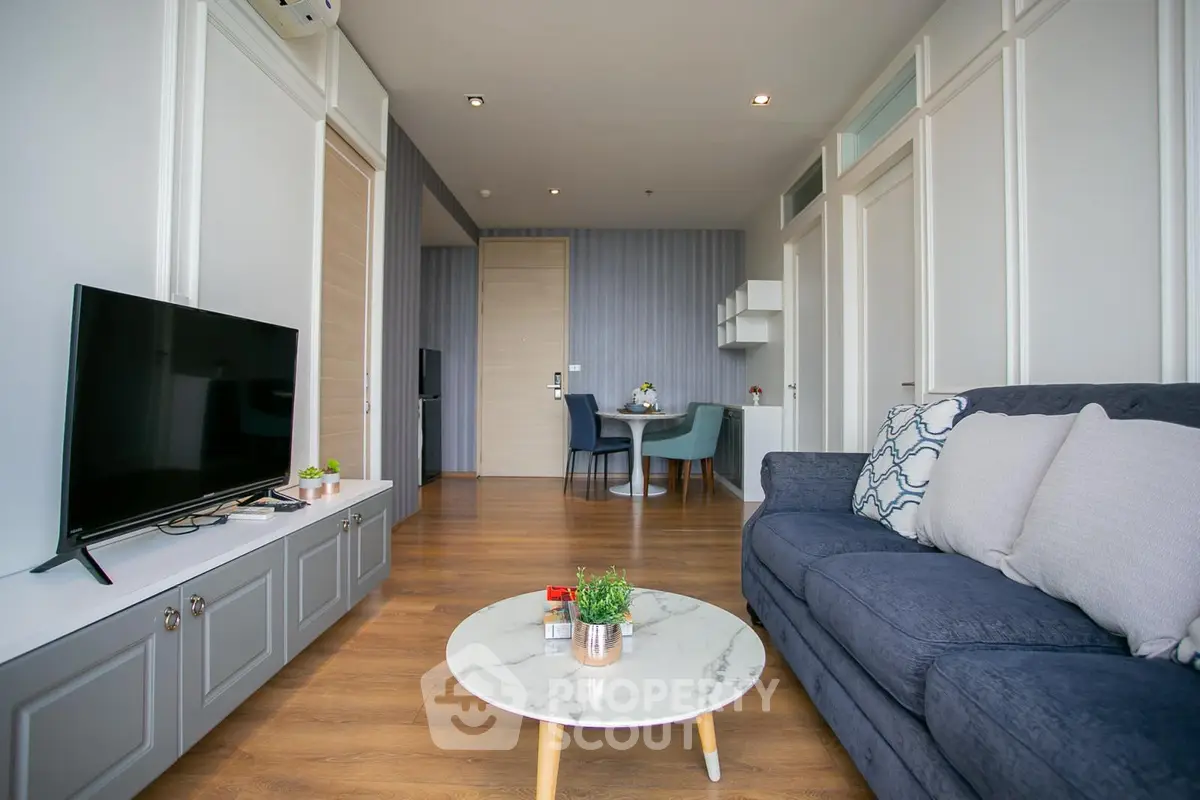Modern living room with stylish decor and open layout, featuring a cozy sofa and sleek TV setup.