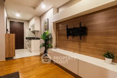 Modern living room with wooden flooring and stylish TV mount, featuring sleek cabinetry and indoor plants.
