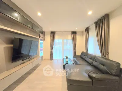 Spacious modern living room with sleek leather sofa and large TV, perfect for relaxation and entertainment.