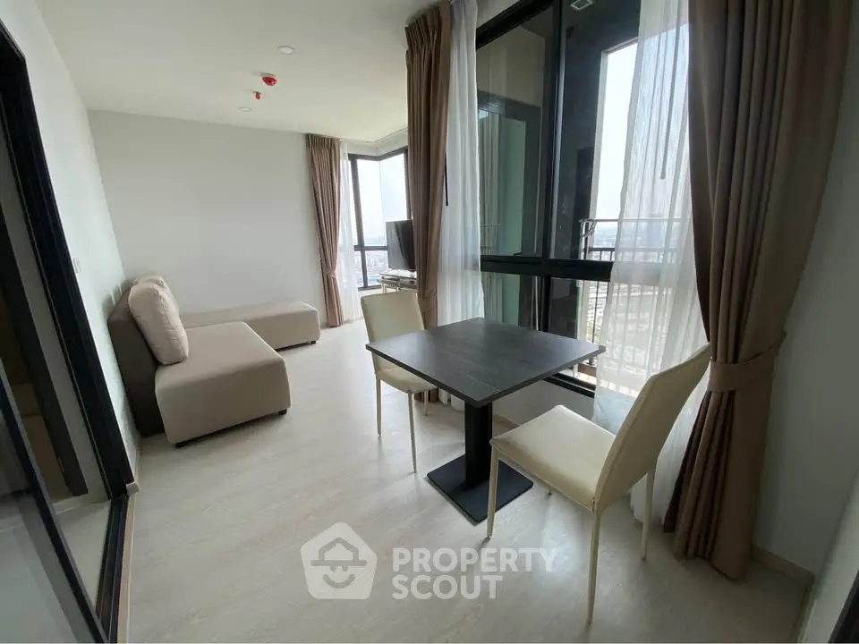 Modern living room with large windows and city view, featuring a cozy sofa and dining table.