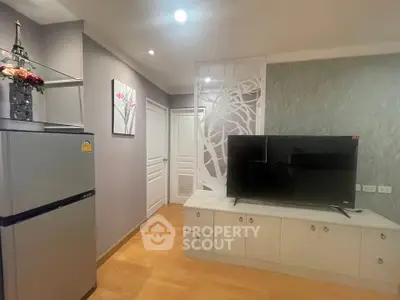 Modern living room with stylish decor and flat-screen TV, featuring a sleek refrigerator and elegant wall art.