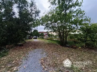 Charming garden pathway leading to a serene residential area with lush greenery.