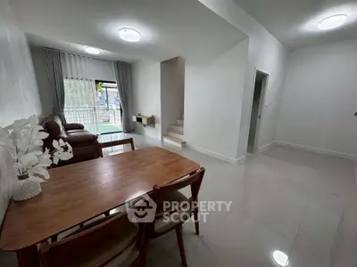Spacious modern living room with dining area and staircase, featuring elegant furniture and natural light.