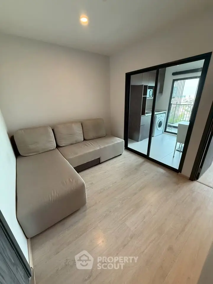 Cozy living room with modern sofa and washing machine view, ideal for urban living.