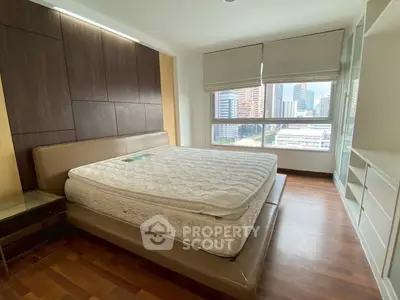 Spacious bedroom with city view and modern furnishings in high-rise apartment