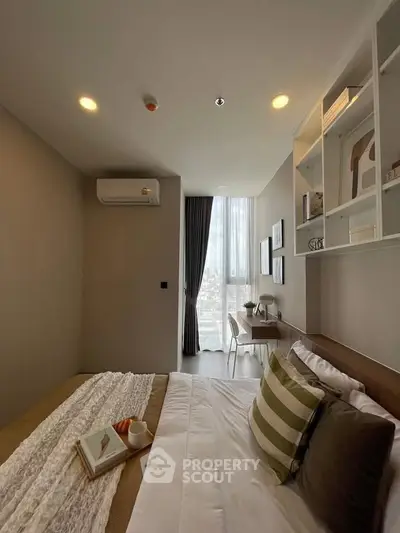 Modern bedroom with stylish decor and city view, featuring a cozy bed and workspace.