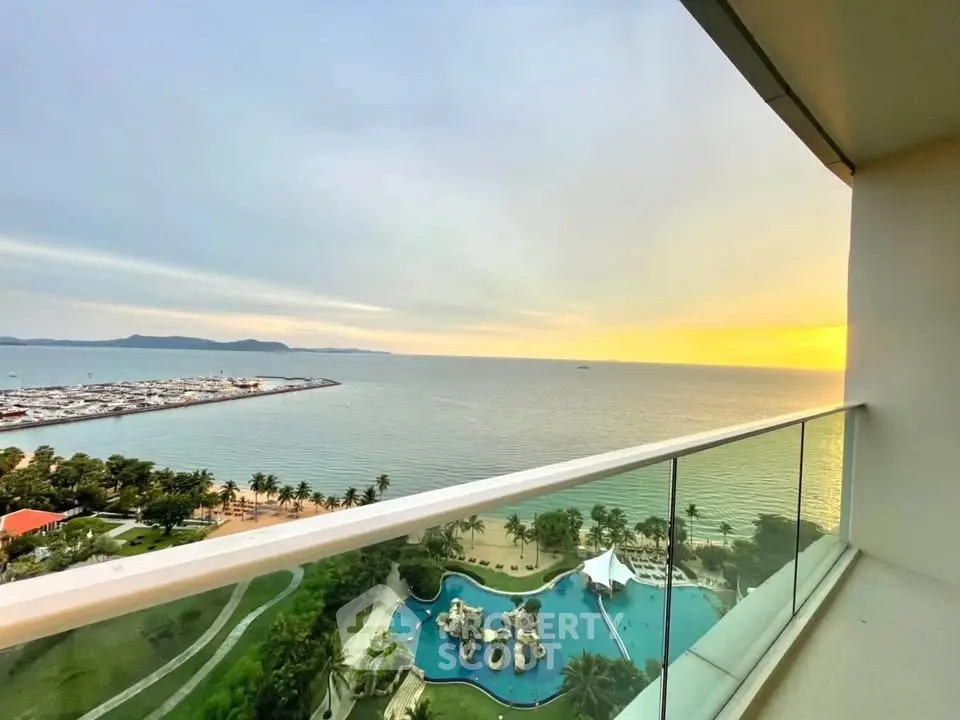 Stunning ocean view from high-rise balcony overlooking pool and coastline at sunset.