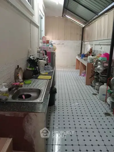 Spacious kitchen with tiled floor and ample counter space, perfect for culinary enthusiasts.