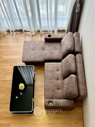 Stylish modern living room with plush sectional sofa and sleek glass coffee table, perfect for relaxation.