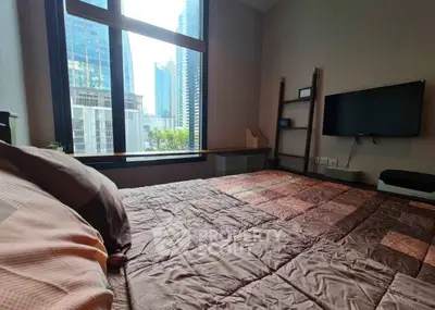 Modern bedroom with city view and wall-mounted TV in urban apartment