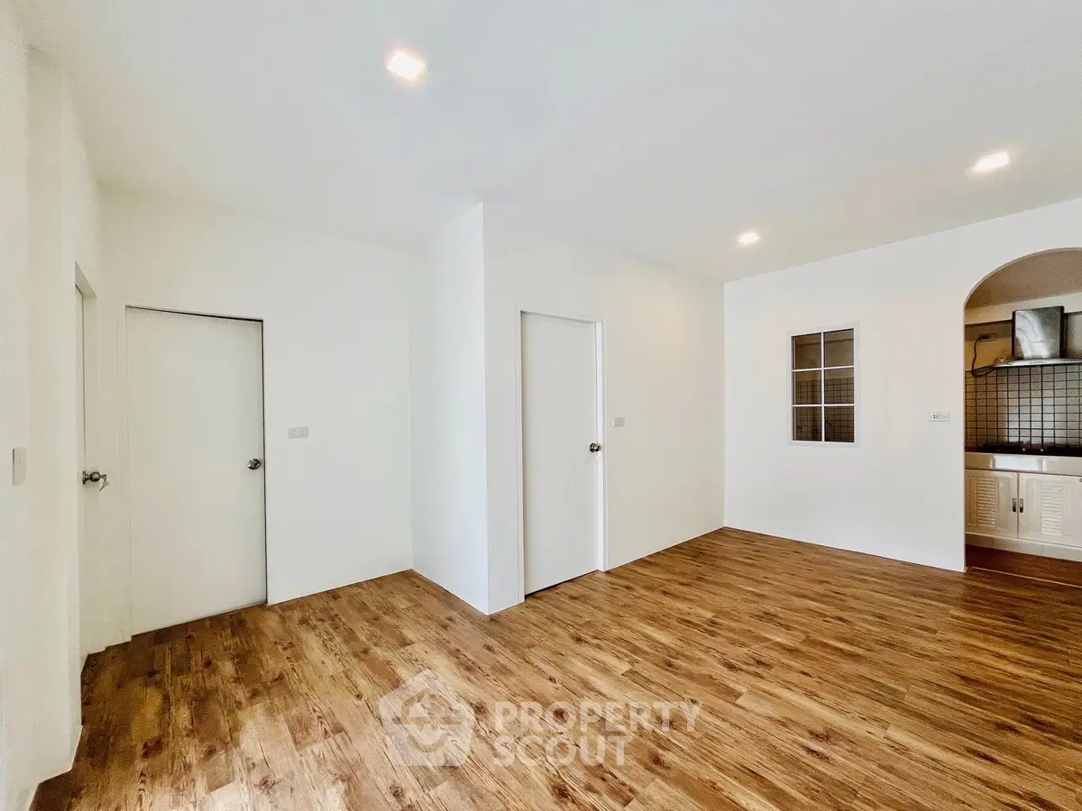 Spacious empty room with wooden flooring and modern lighting