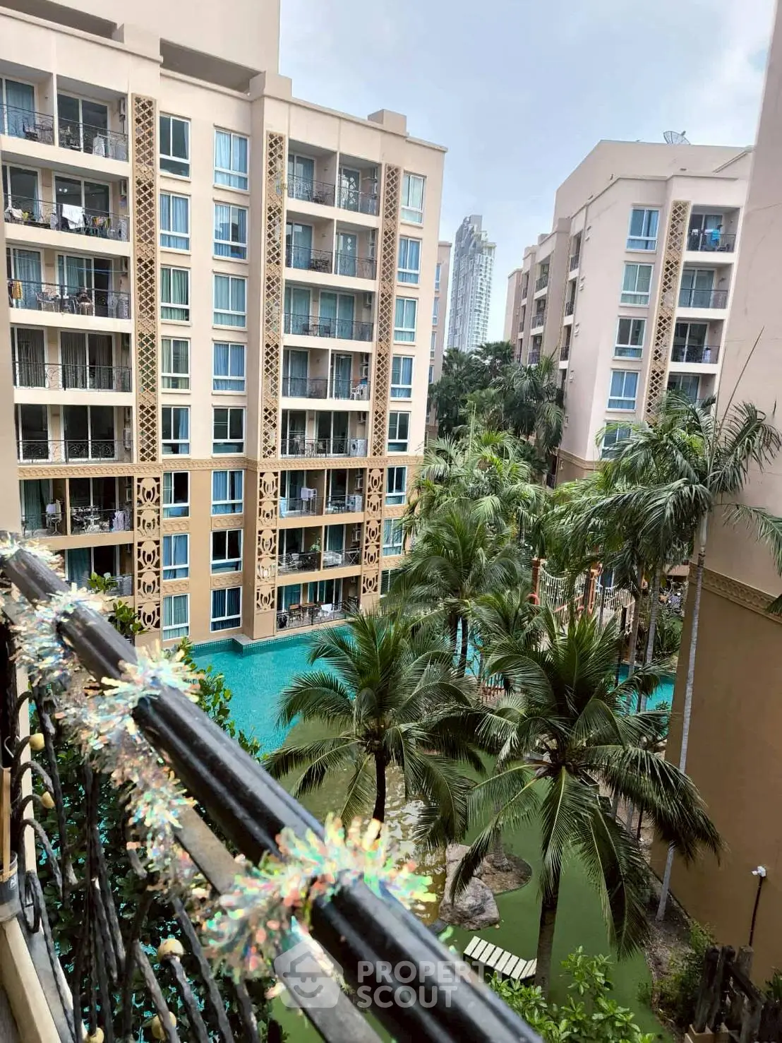 Stunning view of modern apartment complex with lush palm trees and inviting pool area.