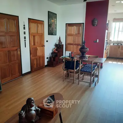Spacious living room with wooden floors and traditional decor, leading to a cozy kitchen area.