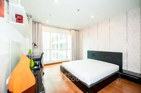 Modern bedroom with large window and stylish decor in urban apartment.