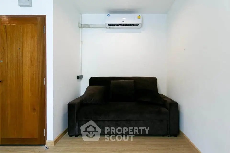 Cozy living room with dark sofa and air conditioning, perfect for relaxation.