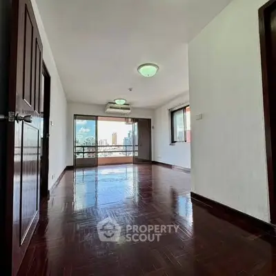 Spacious living room with wooden flooring and city view, perfect for modern living.