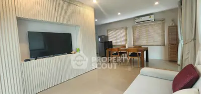 Modern living room with sleek TV setup and dining area, featuring contemporary furniture and natural light.