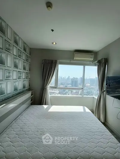 Bright bedroom with city view, modern decor, and wall-mounted TV in high-rise apartment.