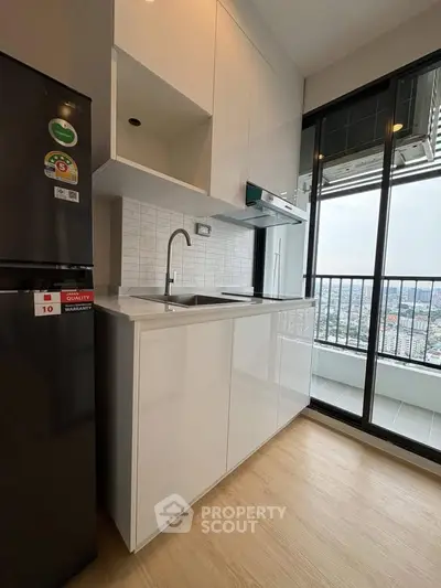 Modern kitchen with sleek cabinets and balcony view in high-rise apartment.