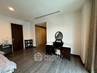 Spacious bedroom with elegant wooden flooring and modern furniture